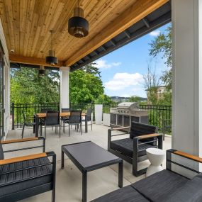 a covered patio with chairs and tables and a grill