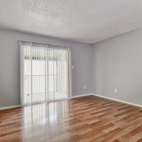 the spacious living room with sliding glass doors and wood flooring