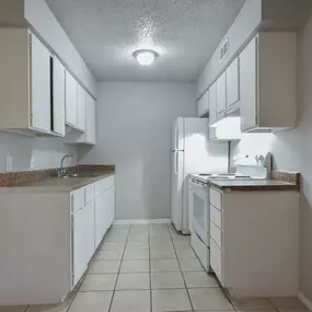 an empty kitchen with white cabinets and a white refrigerator