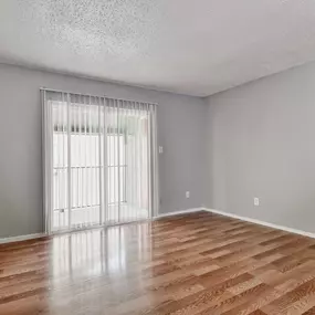 the spacious living room with sliding glass doors and wood flooring