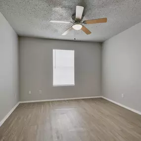 an empty room with wood floors and a ceiling fan