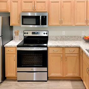 Corner style kitchen with wood cabinets and a stainless steel stove and microwave