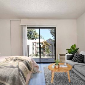 a bedroom with a bed and a couch in front of a sliding glass door