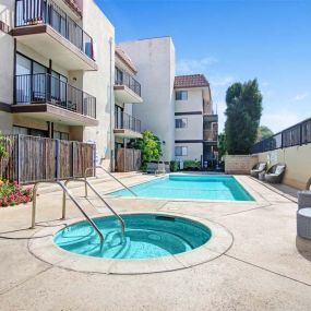 a swimming pool with a hot tub in front of an apartment building