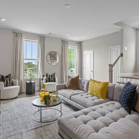 Family room with large tan sectional and staircase in the DRB Homes Towns at Alexander Provence community