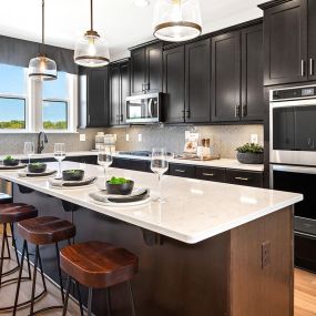 Gourmet kitchen with brown cabinets, stainless steel appliances and island in DRB Homes Vista Gardens West community