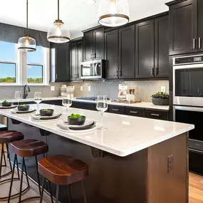 Gourmet kitchen with brown cabinets, stainless steel appliances and island in DRB Homes Vista Gardens West community