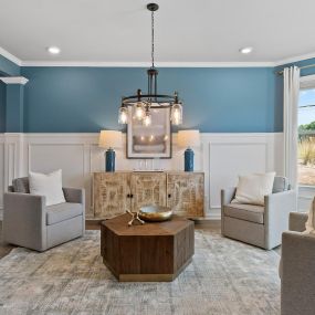 Family room with gray chairs, chandelier and coffee table, blue and white walls in DRB Homes Westminster community