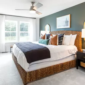 Owner's bedroom with double window, green wall and king bed in a townhome built by DRB Homes Pintail Landing community.