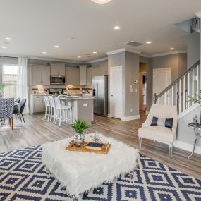 DRB Homes Weavers Ridge Single Family Homes family room with geometric rug, open to dining room and kitchen.