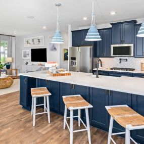 Kitchen with blue cabinets, large island with 3 bar stools.
