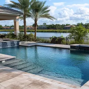 geometric shape pool with spa spillover, stone decking overlooking a lake