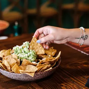 Guacamole dip with cotija cheese sprinkle on top served with corn tortilla chips.