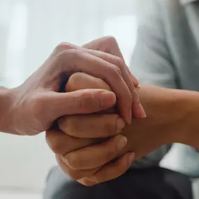 A doctor offers support, holding a patient's hands during Cornerstone's Mental Health Therapy program