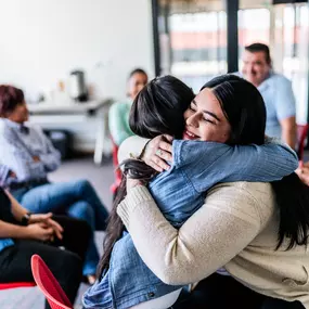 A joyful group shares hugs and support during the Cornerstone of Southern California Group Therapy program in Orange County