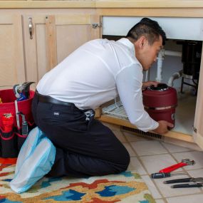Plumber Inspecting and Performing Drain Cleaning Services for a Kitchen Sink
