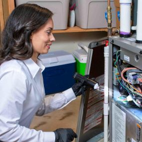 HVAC Technician Inspects A Furnace With Flashlight During Furnace Repair Service Visit