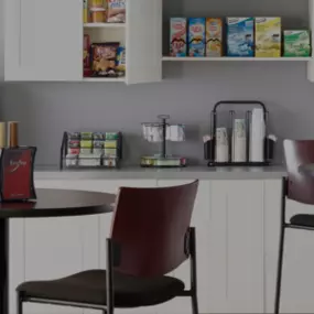 Breakroom essentials featuring coffee dispensers, disposable cups, napkins, and snacks for a well-stocked workspace