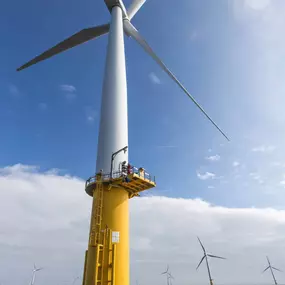 Engineer climbing wind turbine from boat at offshore windfarm