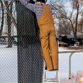 Contractor installing chain link privacy fence