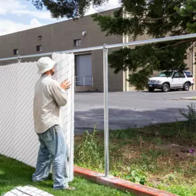 Contractor installing chain link privacy fence