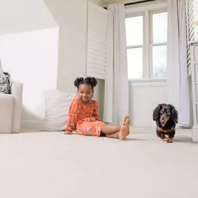 girl and dog playing on carpet