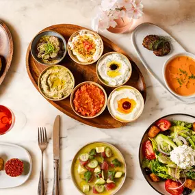 a table filled with mezze, homemade bread, appetizers, and salads