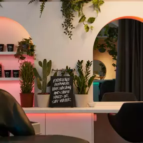 Interior view of the hairlab in Brighton. Archway lit with pink light showing shelves of product. Another arched doorway leading further into the hairlab.