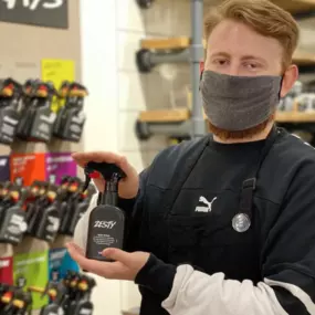 Staff member wearing a face mask holding a body spray