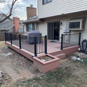 A ground level deck with composite decking with Fortress Black Sand steel railing around the perimeter.