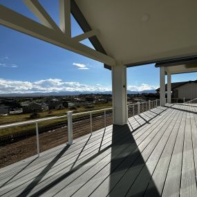 A deck overlooking the mountains with two roof covers over the deck. The deck has White ALX Cable railing with PVC Decking.