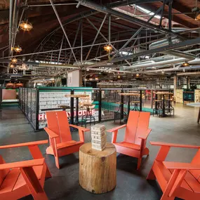 This image shows a casual seating area at Punch Bowl Social, complete with orange Adirondack chairs and a wooden Jenga game set. The space is perfect for relaxing and enjoying light-hearted activities.