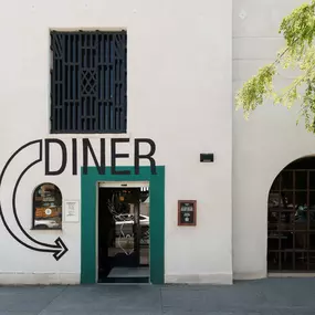 This photo captures the exterior of Punch Bowl Social's Diner entrance, featuring bold signage and a modern design with green trim. The clean, minimalist look adds to the venue's urban aesthetic.