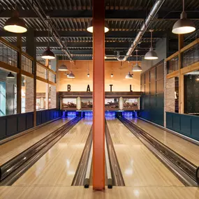 This image captures the bowling lanes at Punch Bowl Social Atlanta, featuring a modern, industrial design. The warm lighting and clean lines create a sleek and stylish atmosphere for bowling.