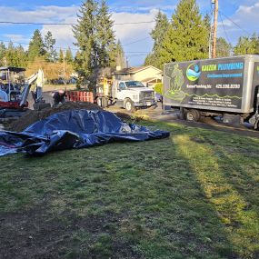 Kaizen Plumbing service trucks and excavation setup at a residential property.