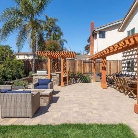 Paver patio, pergolas, fire pit, BBQ island with pergola, grass and plants - backyard in Ventura