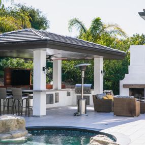 Outdoor kitchen under a custom built cabana near a swimming pool