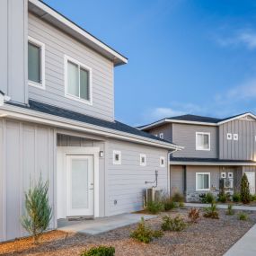 Front view of townhome buildings with gravel landscaping with manicured bushes throughout