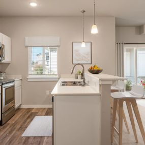 Side view of kitchen countertops with bar stool seating with a view of the living room and sliding glass doors