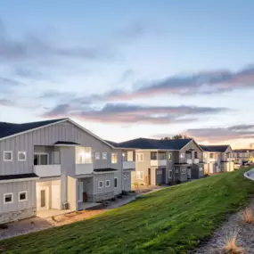 View of property buildings with grassy hill in front at dusk