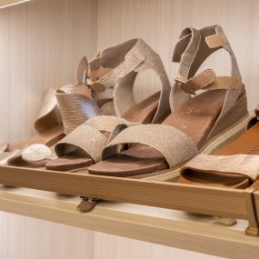 Sandals on slanted shoe shelves with matte gold shoe rails