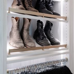 Slanted shoe shelves with shoe rail holding leather boots