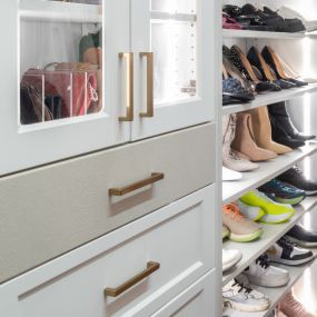 A leather drawer front adds a pop of color and texture to this white closet.