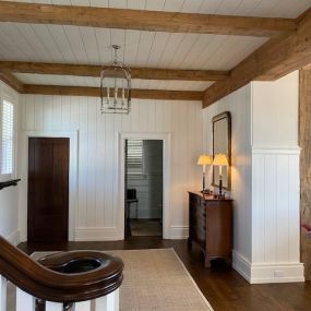 This Entry hall is wrapped in White shiplap and accented with reclaimed wood ceiling beams and tied into a 12