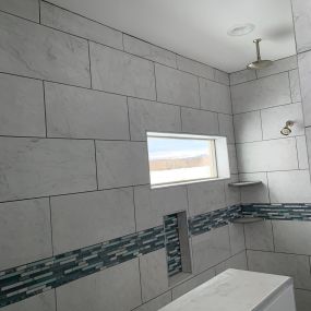 An open shower with white marble tiles, featuring both a rain head and a wall head. The sleek and pristine white marble tiles create a clean and elegant aesthetic, while the dual shower heads provide a refreshing and invigorating showering experience.