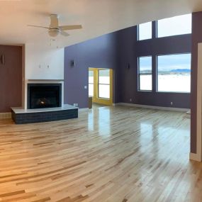 Cozy living room with fireplace, white pine floors, large windows, and eclectic colored walls for a vibrant and creative ambiance.