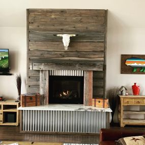 A restored barnwood fireplace takes center stage, with corrugated metal accents and a striking bison skull. The rustic barnwood, industrial metal, and the bison skull creates a captivating focal point, adding character and charm to the space.