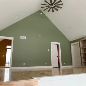 Upstairs landing with a white pine floor, accentuated by one vibrant green wall and one striking purple wall. The combination of the natural wood flooring and the bold wall colors creates a unique and visually captivating space.