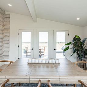 Bright dining room in log cabin with white oak floor and stone fireplace, blending rustic charm with contemporary elegance.