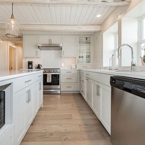 A log cabin kitchen with its modern design and bright finishes. The combination of rustic charm, showcased through the log cabin aesthetic, and the contemporary elegance of quartz countertops and stainless steel appliances creates a stunning space.